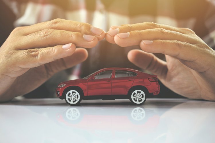 Close up to a pair of hands covering a toy car to illustrate different types of car insurance