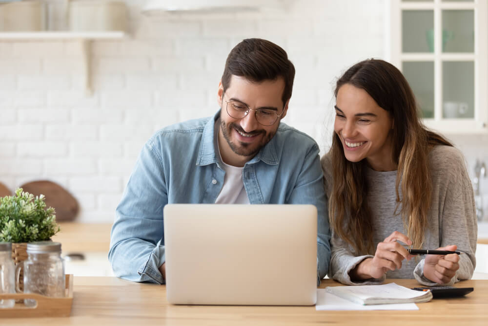happy couple learning how to save money con car insurance in laptop