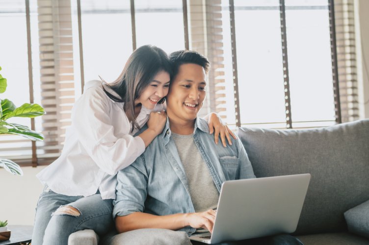 happy asian couple in home with laptop looking for comprehensive insurance in california