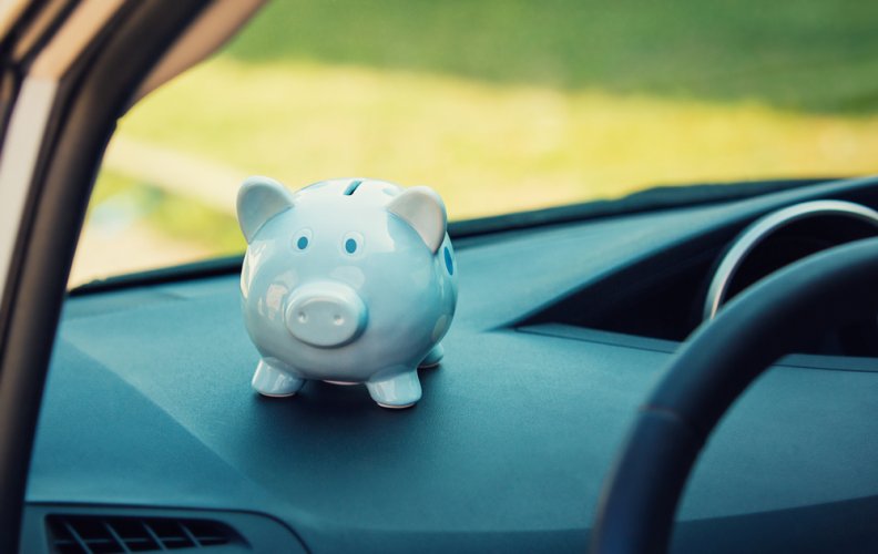 A piggy bank placed on car dashboard to represent savings in auto insurance