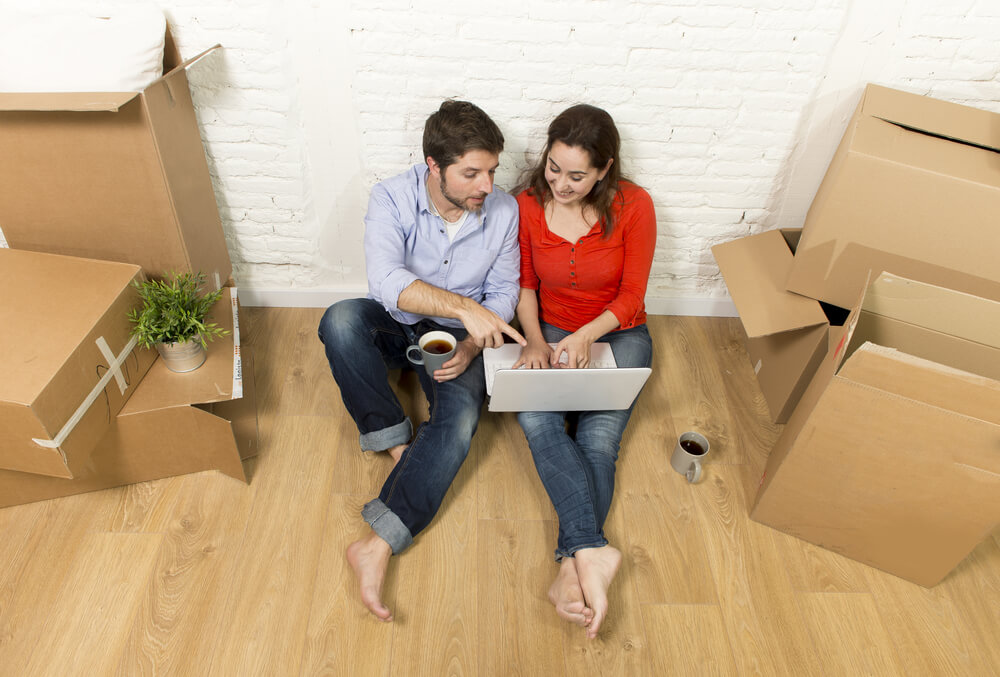 young happy couple on floor of home saving in insurance with laptop