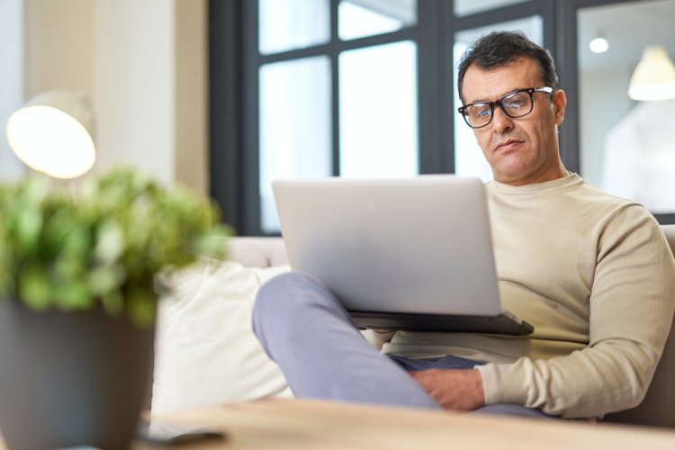 hispanic man in couch looking at laptop for car insurance after a dui