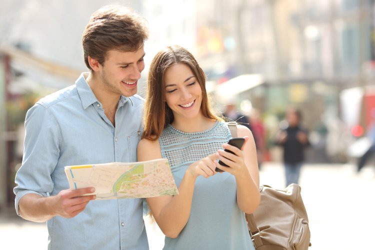 happy tourist couple looking at map and phone