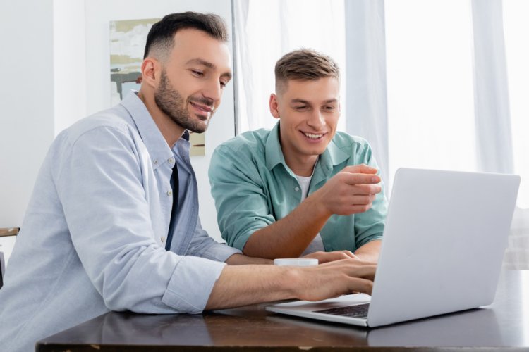two men looking at car insurance coverage in laptop and smiling