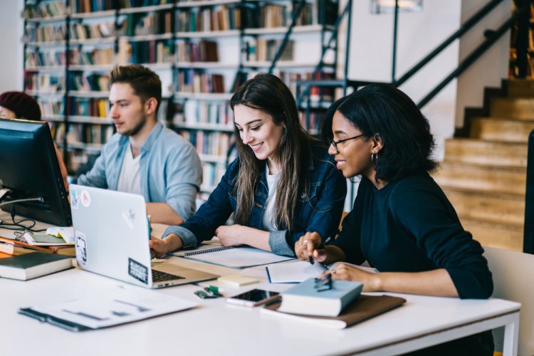 diverse group of college students studying in library