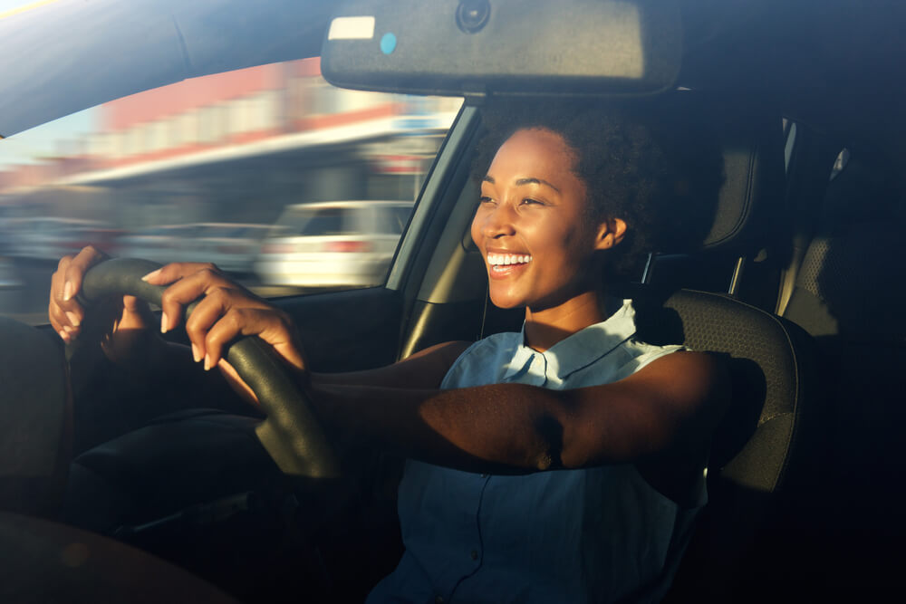 Portrait of smiling young african american woman driving a car