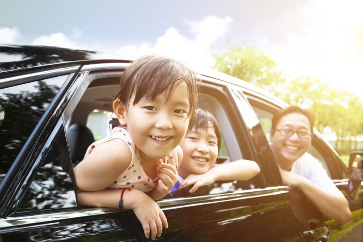 happy little girl with family sitting in the car during a trip with insurance