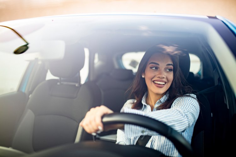 smiling hispanic woman driving car with insurance