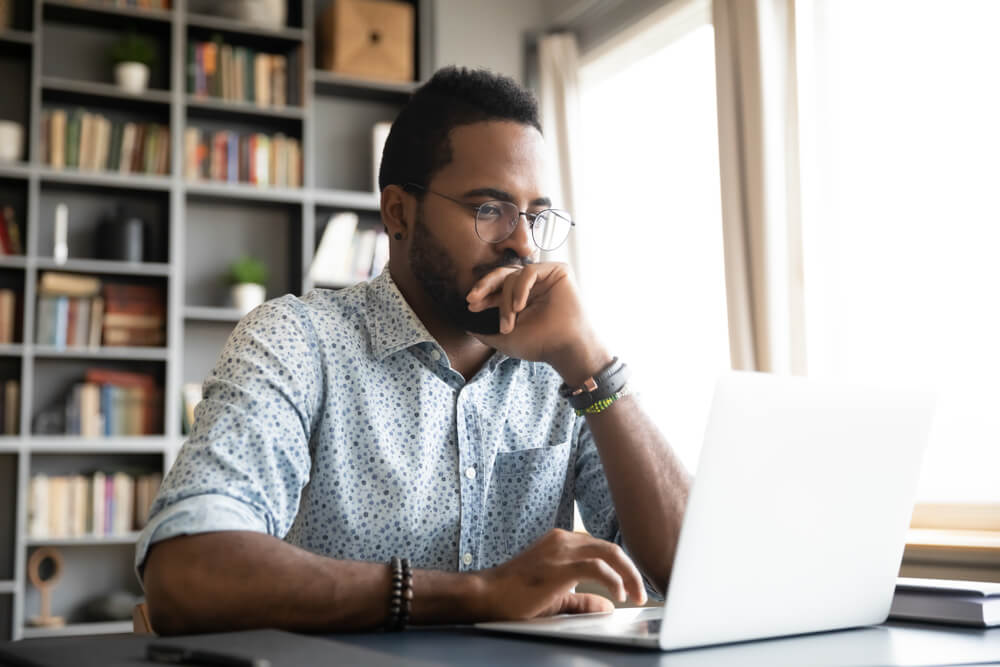 focused young african american man looking for car insurance in laptop