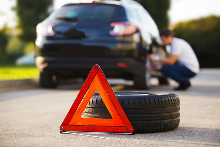 emergency road sign in the front with a tire and a car in the background