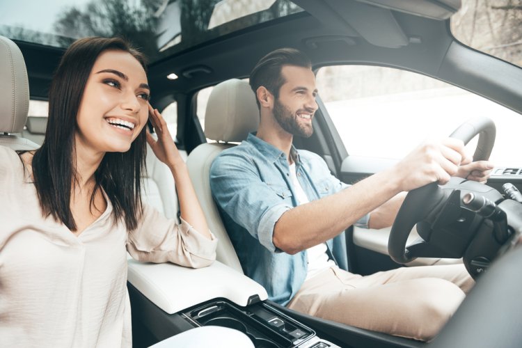 sideview of happy couple in car with the man driving