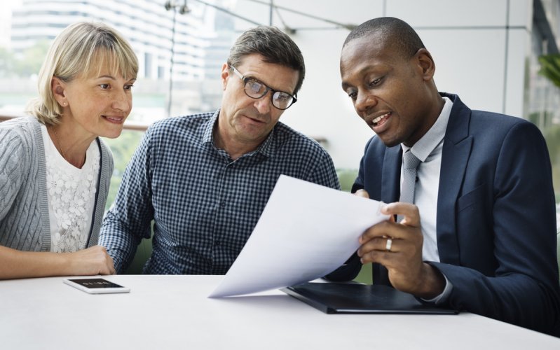 older couple with car insurance agent looking at paper policy