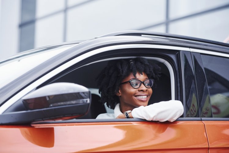 Young african american woman sits inside of new modern car