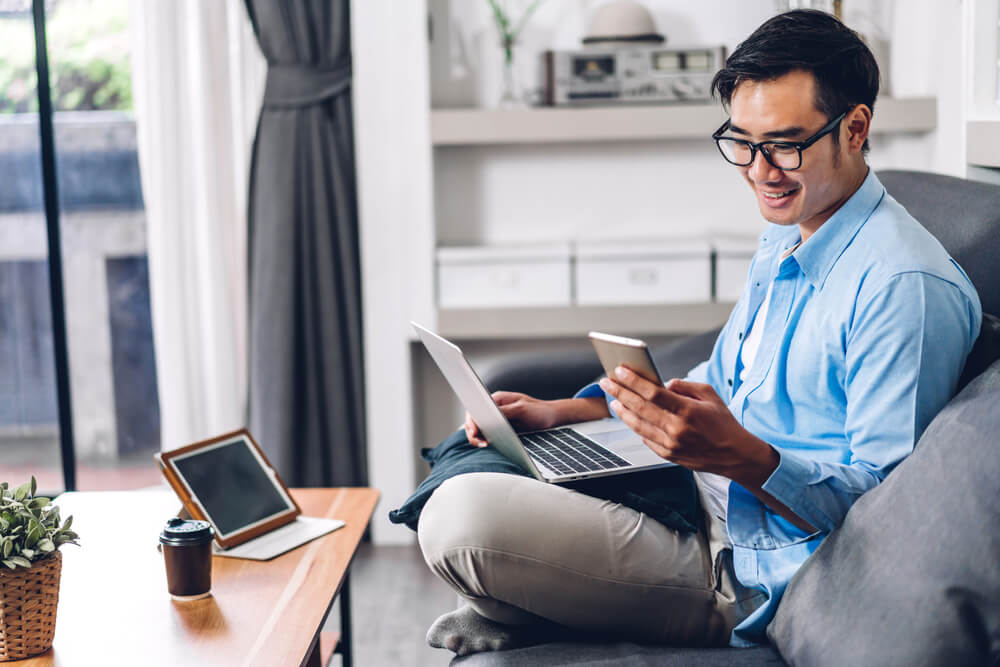 Young smiling asian man relaxing using laptop for renters insurance in california