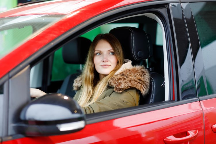 young Caucasian woman driving red car