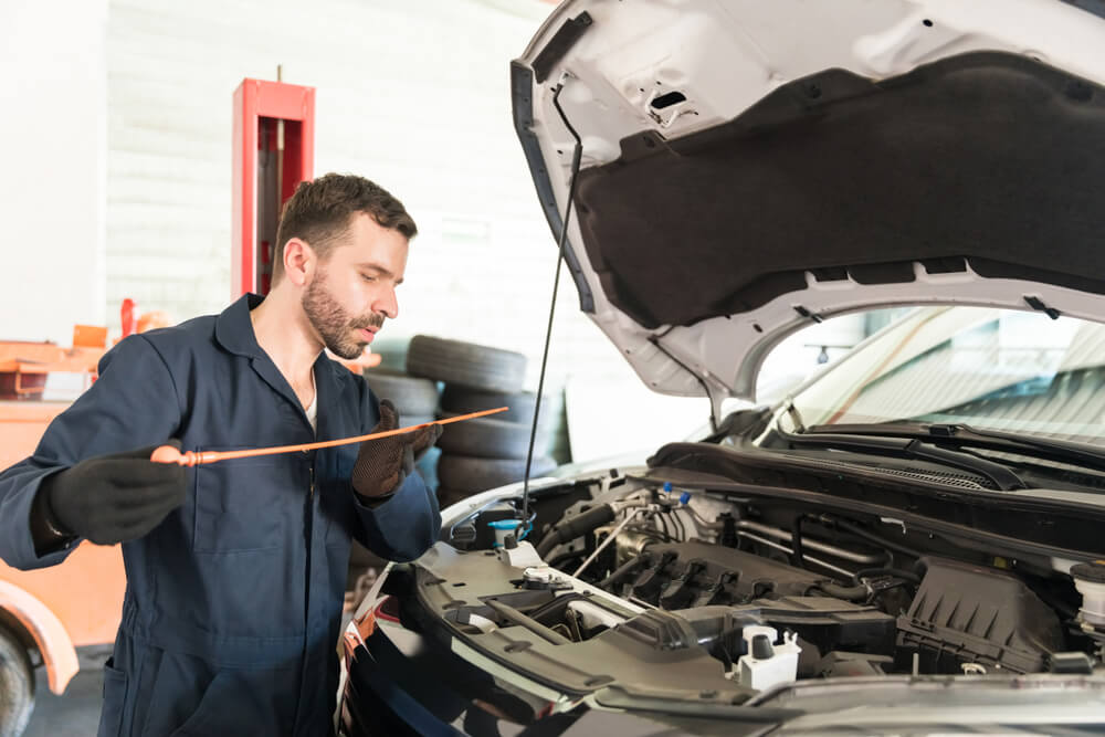 car mechanic working under hood of vehicle