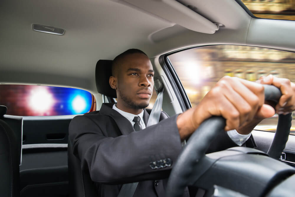 young man getting pulled over with cop lights behind him