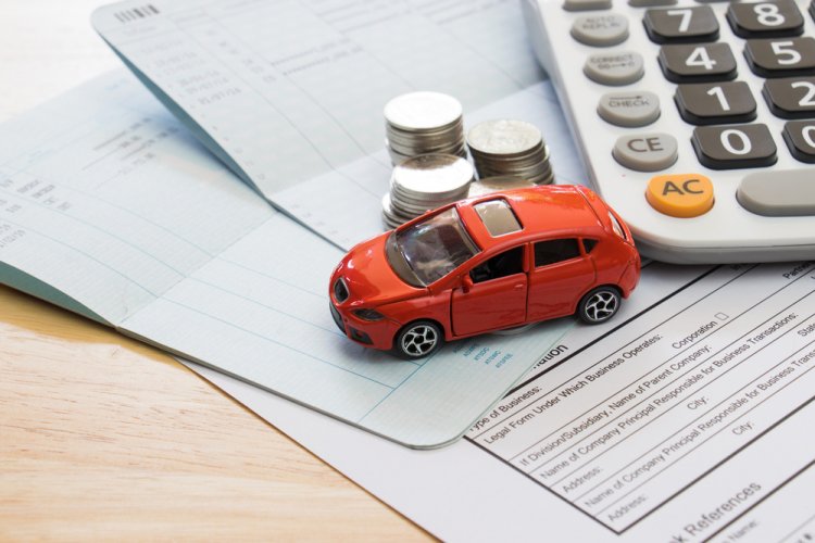 paperwork with toy car, calculator and coins on top of it