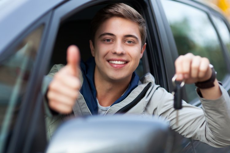 young caucasian male with thumbs up in driver's seat of car holding keys