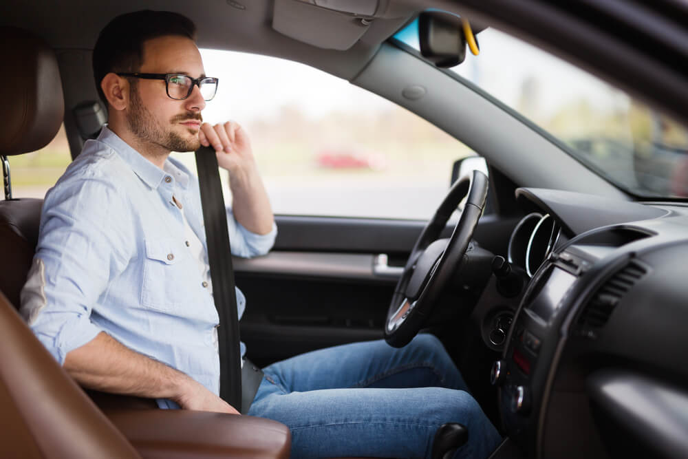 man buckling seat belt in car