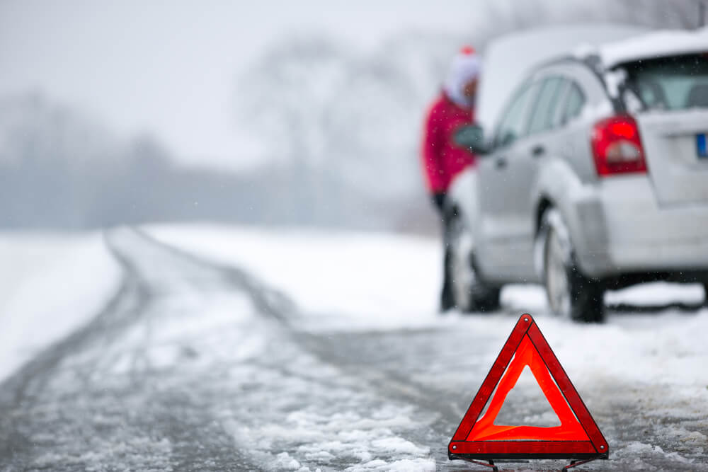 car stranded on side of road in winter weather