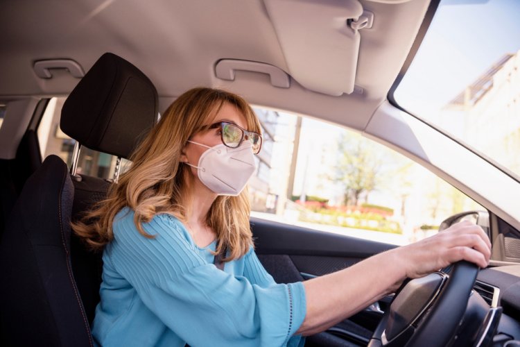 woman with mask on driving car