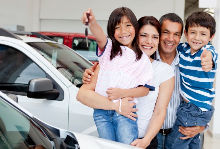 asian family smiling with new car keys at car dealership