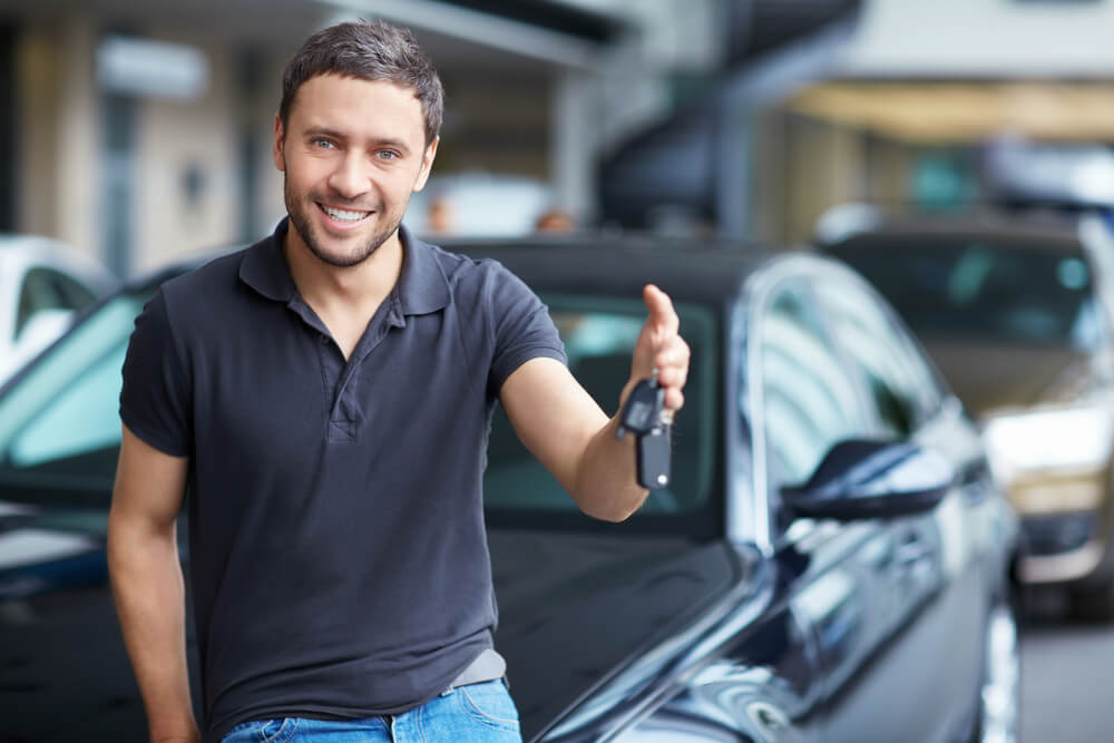 Young man dangles car keys for rental car