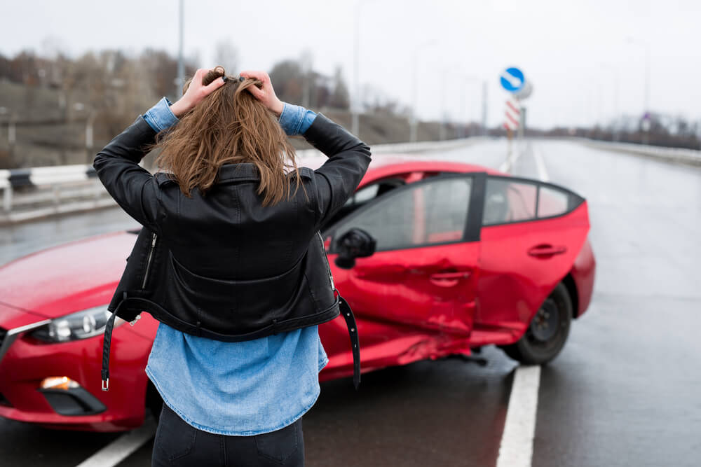 Young women tears her hair out over a car accident on a wet road