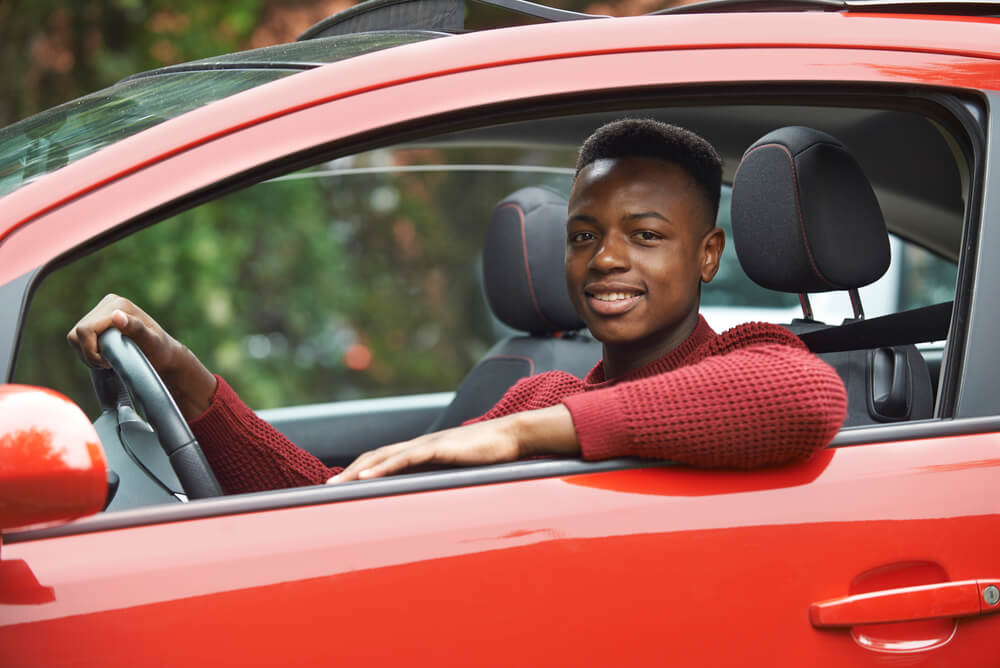 Male Teen Driver Looking Out Of Car Window