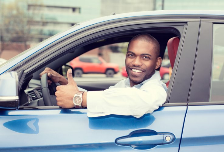 african american male driver leaning out of car with thumbs up smiling