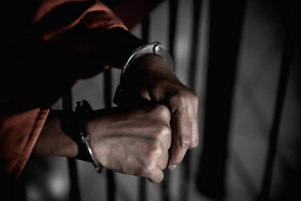 Hands in handcuffs through jail cell bars