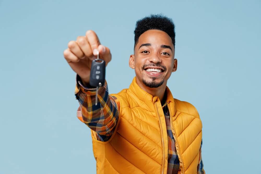 Young African American man holds key to a car