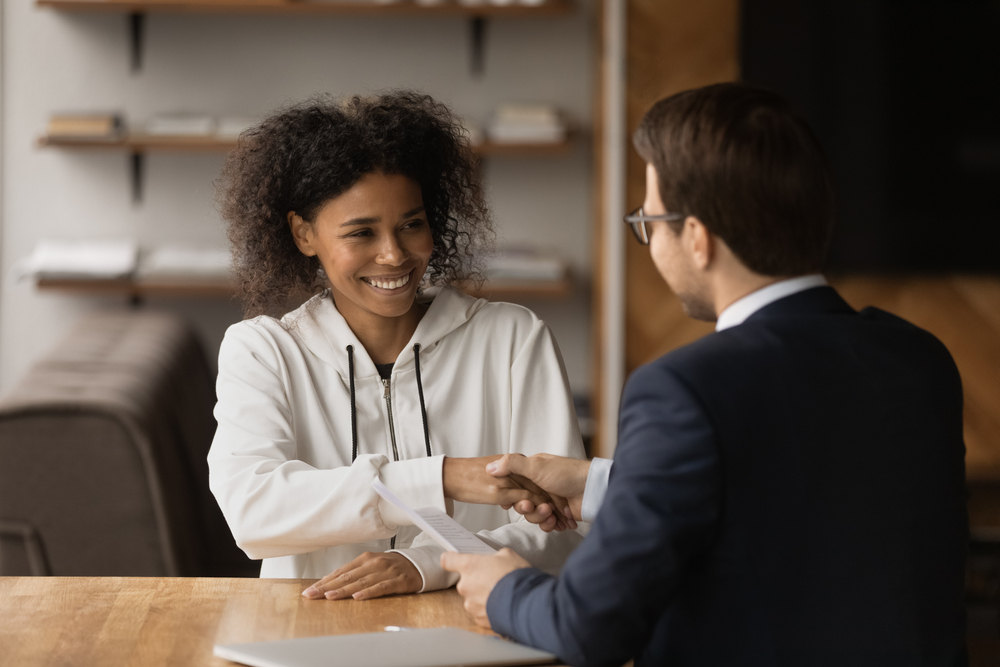 Smiling African American woman shakes hands with insurance man after getting the best deal on car insurance