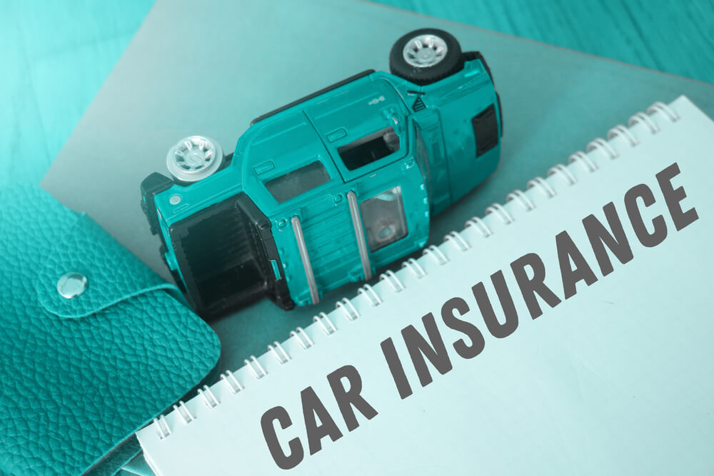 Toy car on its side with what is a car insurance deductible notebook