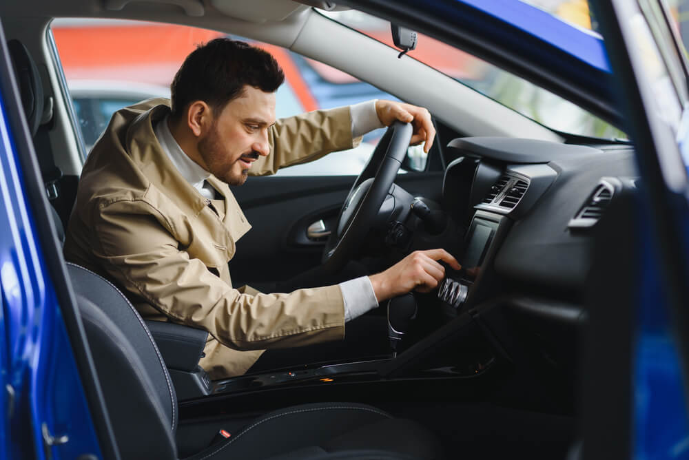 Hispanic man selecting radio station while driving with SR-22 insurance