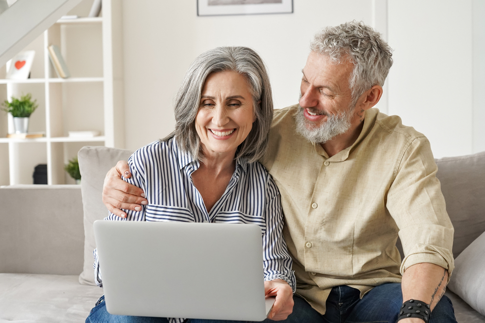 Older couple smiles happily as the buy car insurance online