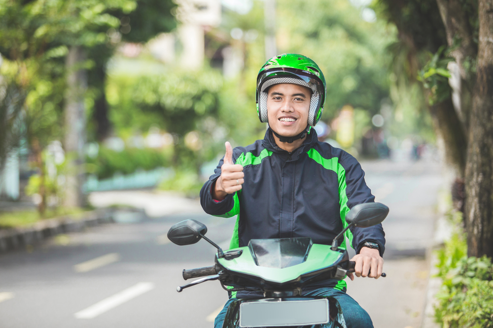 Young Hispanic man giving thumbs up wearing motorcycle helmet