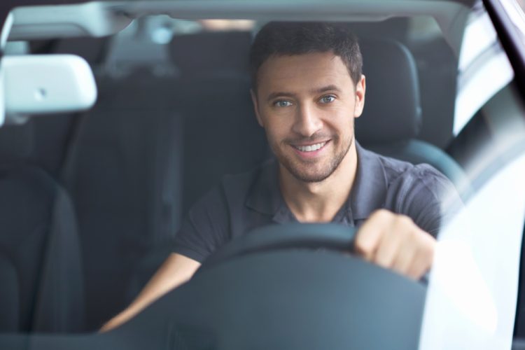 caucasian man behind wheel of car smiling