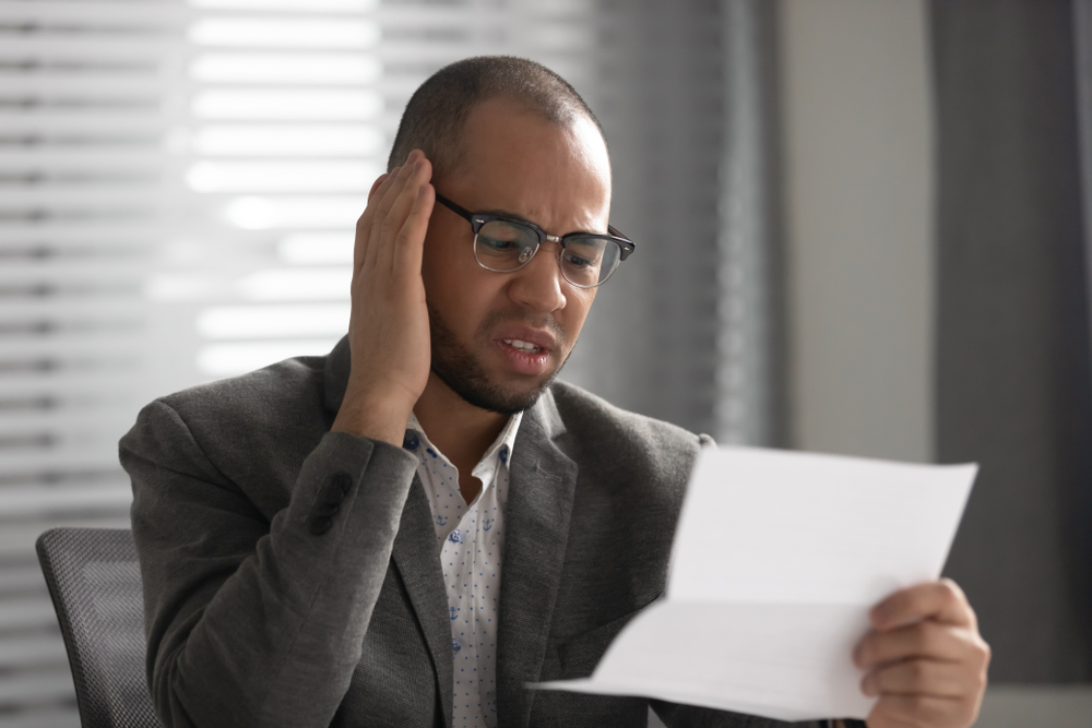 Confused and unhappy African-American man tries to understand auto policy