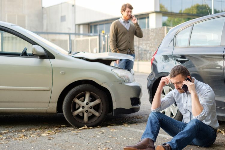 two men standing by two wrecked cars