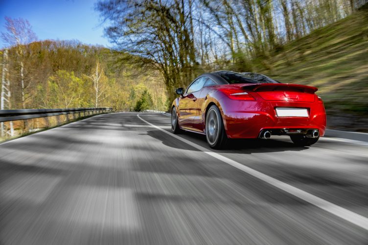 red car driving down road