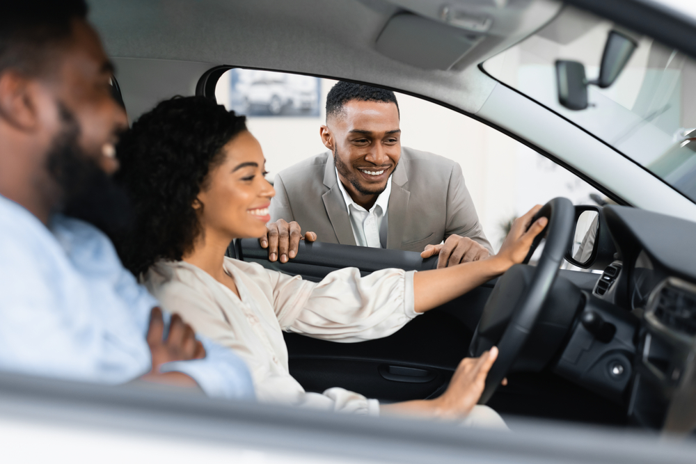 African-American couple wonders how to beat the car salesman as they shop for a new car