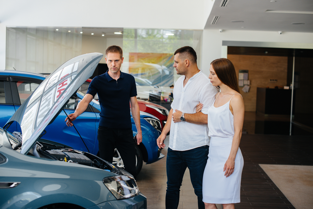 Hispanic couple checks for brand new car issues at the dealership