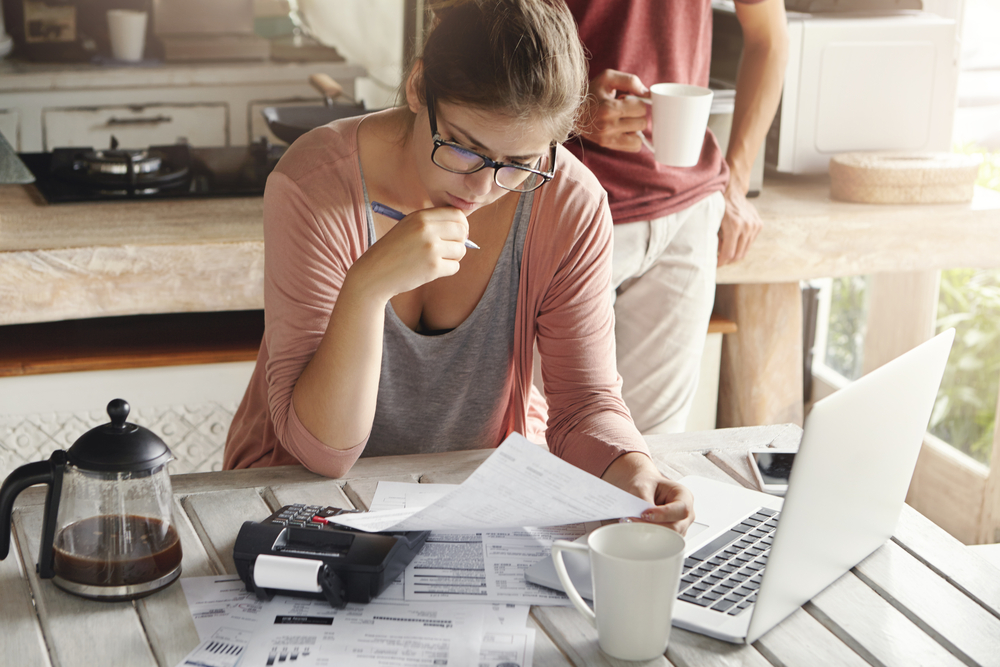 woman sitting near laptop looking over insurance paperwork