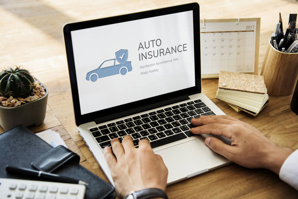 Person reviewing auto insurance information on a laptop to understand what makes you a high-risk driver.