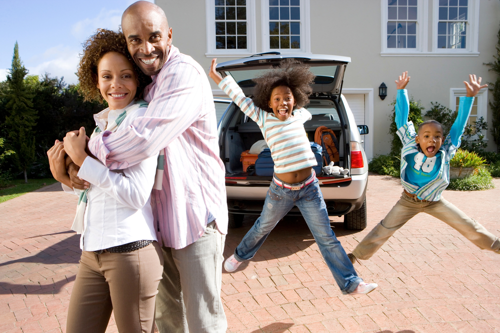 Happy African American family with car and house in background