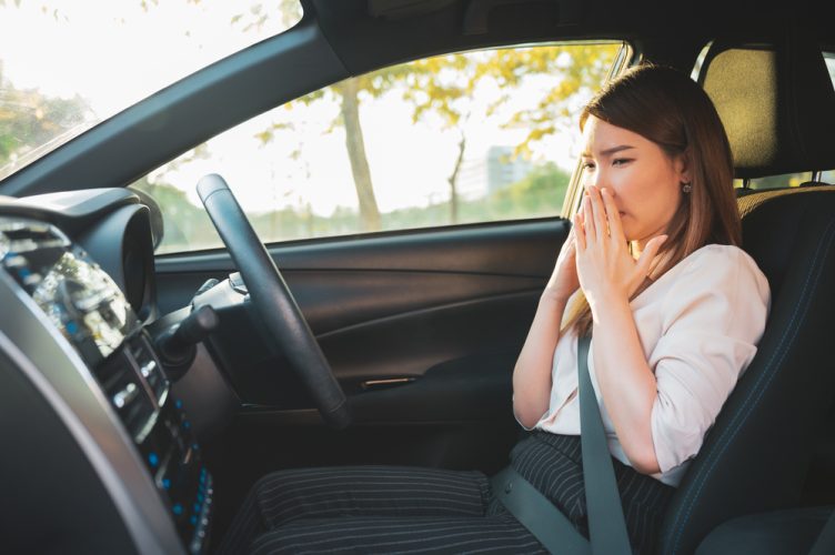 Young woman smells something bad in the car