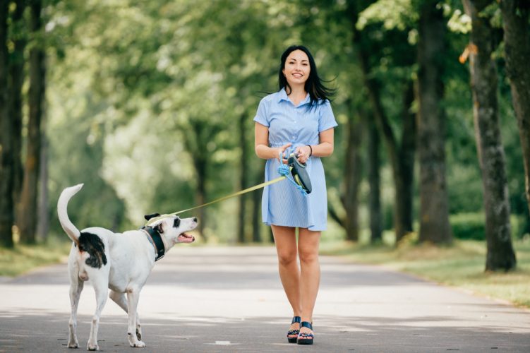 smiling woman walks her dog in the woods