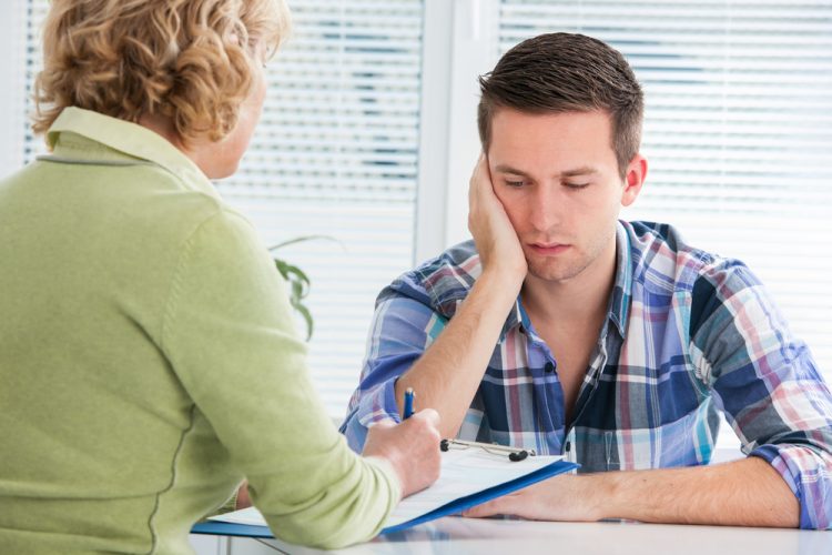 Worried young man contemplates how he will pay for his healthcare now that the PHE is ending